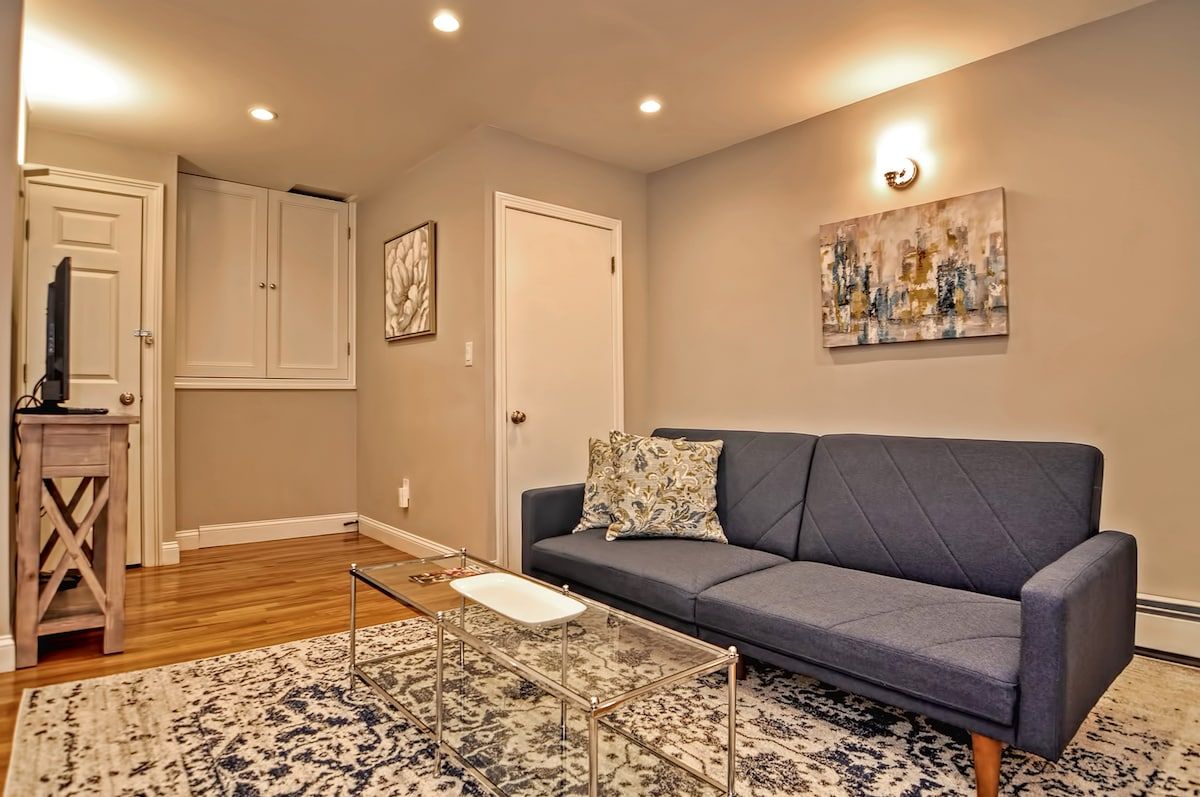 Cozy living room with gray sofa and glass coffee table on a patterned rug.