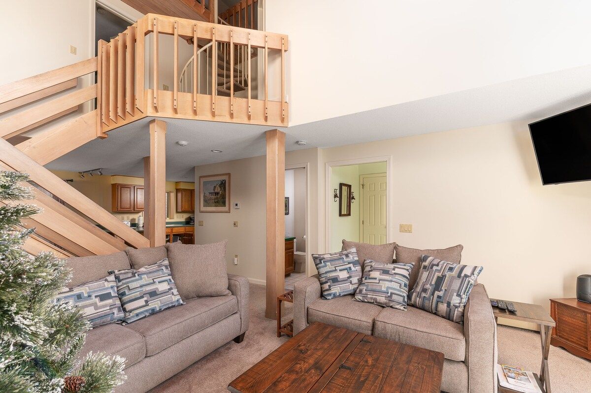 Cozy living room with a staircase leading to the loft area and a comfortable couch