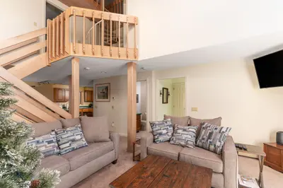 Cozy living room with a staircase leading to the loft area and a comfortable couch