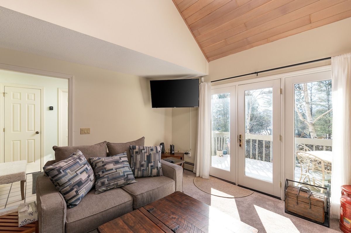 Cozy living room with a comfortable couch and large windows overlooking the deck