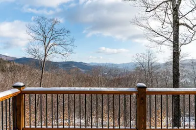 A snow-covered deck with a view of the mountains and trees in the background.