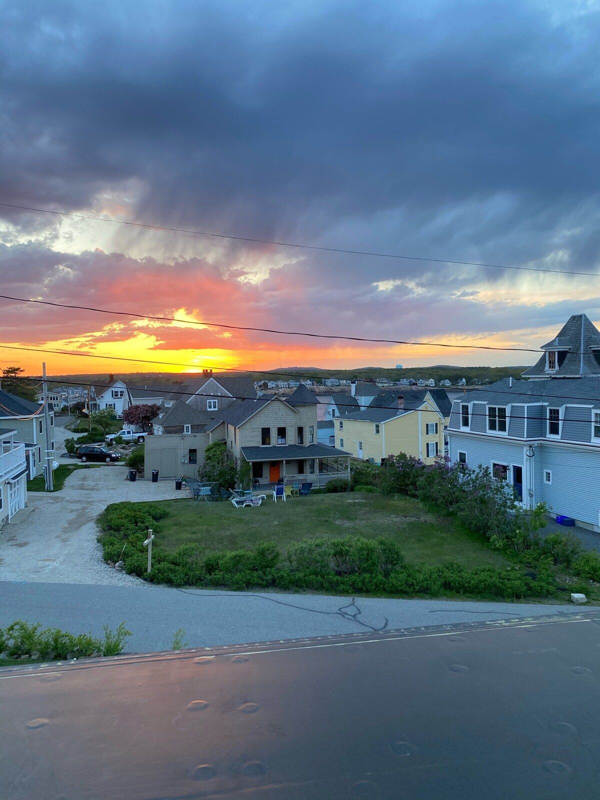A neighborhood street with houses and a sunset in the background.