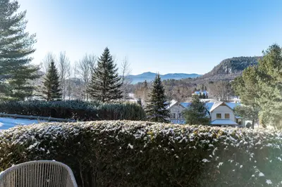 Snowy winter landscape with a house and mountains in the distance