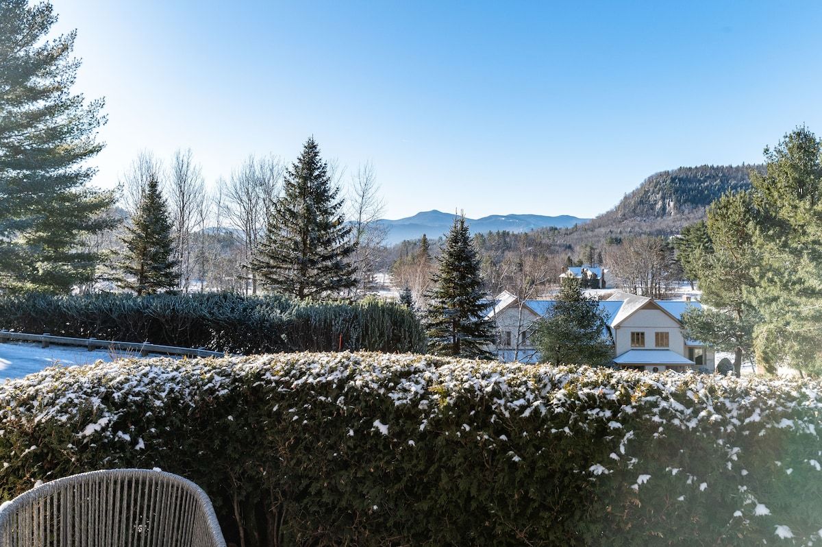 Snowy winter landscape with a house and mountains in the distance