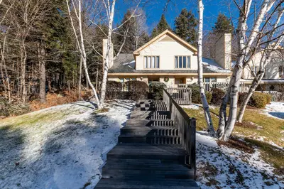 Snowy yard with a wooden staircase leading to the front door of a two-story house