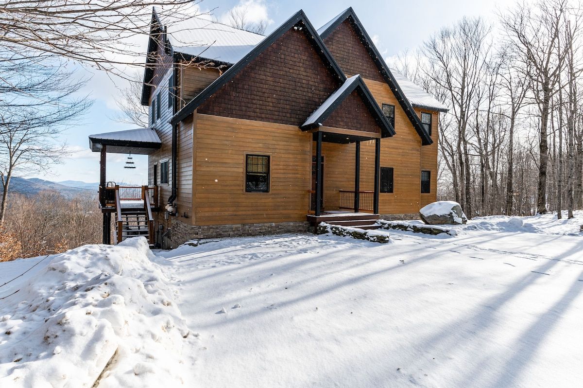Snowy winter landscape with a large house and mountain views
