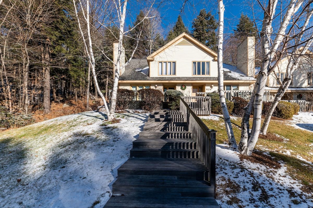 Snowy yard with a wooden staircase leading to the front door of a two-story house