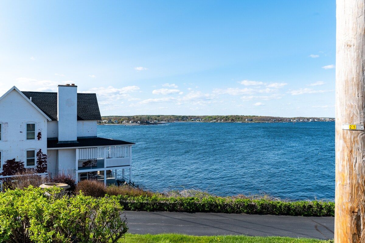 A large white house with a balcony overlooking the ocean.