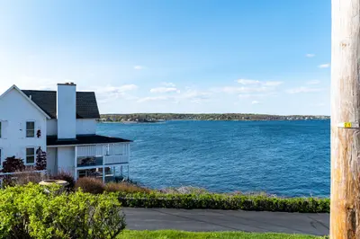 A large white house with a balcony overlooking the ocean.