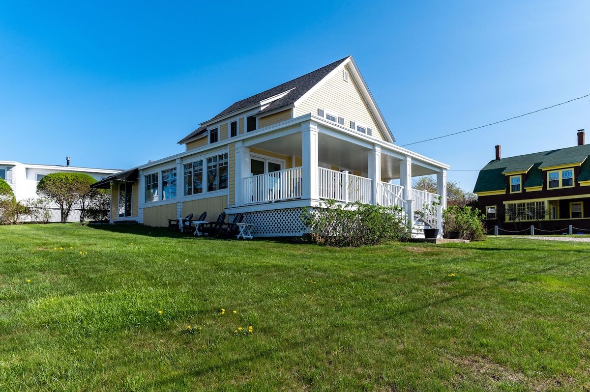 Large front porch with a white railing and a green roof